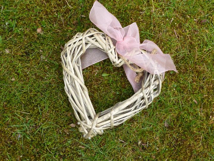 rustic_pink_ribbon_heart.jpg - Rustic handcrafted wicker heart with pink ribbon tied in a bow symbolic of love and romance lying on green grass for Valentines, a wedding or Mothers Day