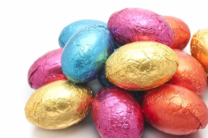 easter_egg_pile.jpg - Colourful pile of Easter Eggs wrapped in multicolour shiny foil on a white studio background