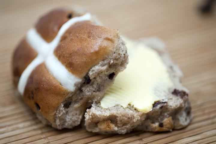 buttered_hotcross_bun.jpg - Freshly baked spicy traditional Easter hot cross bun sliced in half and buttered