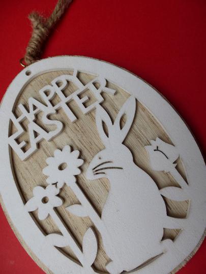 wooden_bunny_sign.jpg - Wooden laser cut pendant with white Easter bunny and spring flowers, viewed in close-up on dark red background