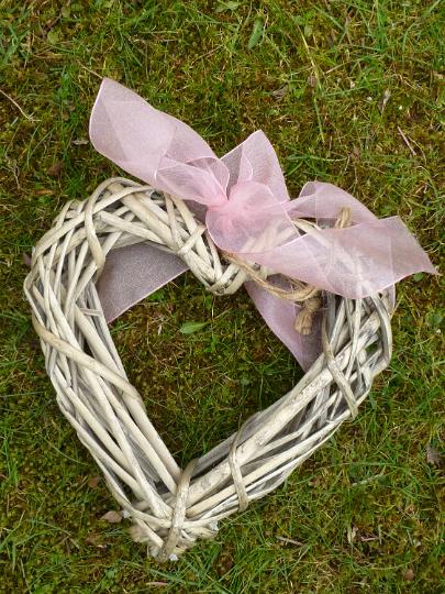 rustic_heart.jpg - Rustic handmade wicker heart with pink ribbon bow lying outdoors on green grass symbolic of love and romance, a wedding or Valentines Day