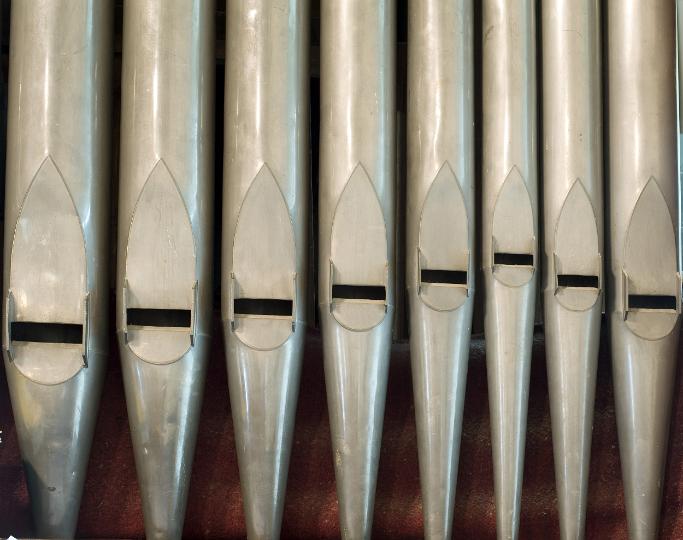organpipes.jpg - Closeup view of a row of metal church organ pipes, a wind instrument played to produce music during worship and services