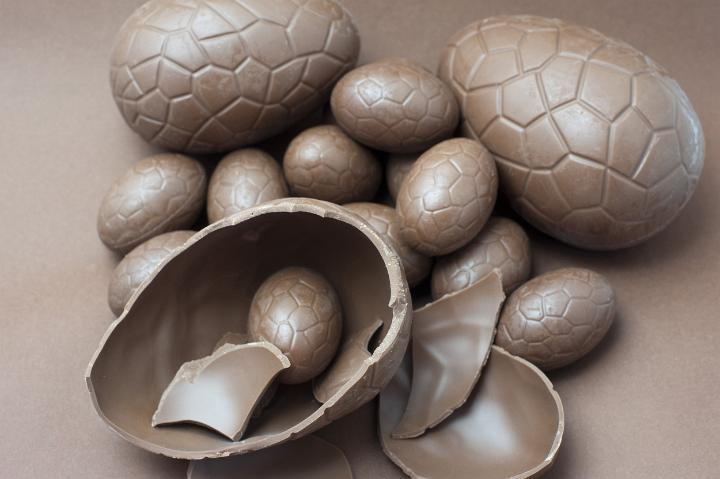 chocolates.jpg - Assorted milk chocolate Easter Eggs on a brown background with one broken egg in the foreground