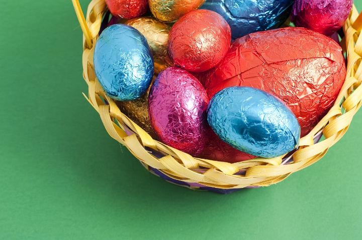 easter_corner.jpg - Corner of colourful Easter Eggs of varying sizes in shiny foil wrapping collected in a wicker basket