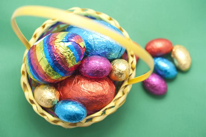 egg_basket.jpg - Colorful chocolate Easter Egg basket with a collection of different sized and coloured eggs on a green background