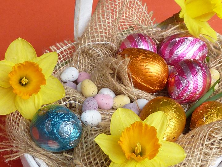 still_life_easter.jpg - Basket of Easter eggs treatments and yellow narcissus flowers. Chocolate eggs and mini egg candies in sack cloth, viewed in close-up