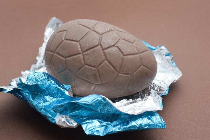 chocolate_easter_egg.jpg - Close up shot of chocolate Easter egg and blue foil on brown background