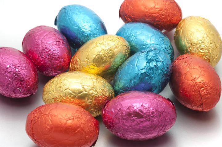 easter_egg_colors.jpg - Collection of multicoloured Easter Eggs wrapped in different coloured shiny foil wrappers spread out randomly