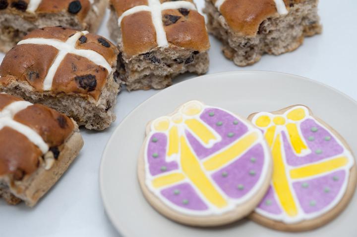 easter_treats.jpg - Scrumptious fresh spicy Hot Cross buns and Easter cookies in the shape of decorated eggs laid out ready for eating
