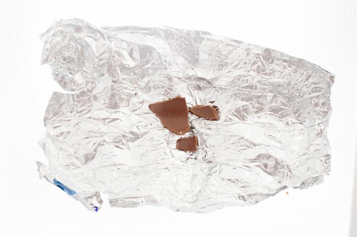 eaten_chocolate.jpg - Remnants of an eaten chocolate Easter egg on the silver tin foil wrapping isolated on white