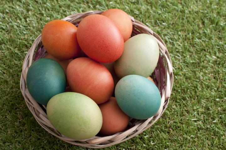 basket_of_easter_eggs.jpg - Colorful eggs fill woven easter basket in grass having been painted green and red