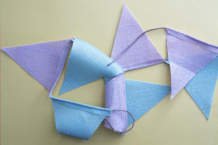 easter_bunting_decorations.jpg - Top view of blue and purple easter bunting decorations on beige background