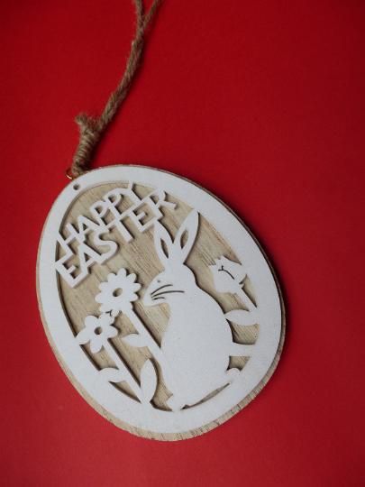 red_bunny_easter.jpg - Small carved wooden pendant with Happy Easter sign and white bunny among flowers, sitting on plain red background with vignette effect