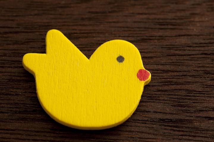 wood_easter_chick.jpg - Cut and painted wooden chick for Easter holiday. View from above over dark wood table.
